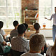 Image of a person speaking to a group of people in a workshop setting